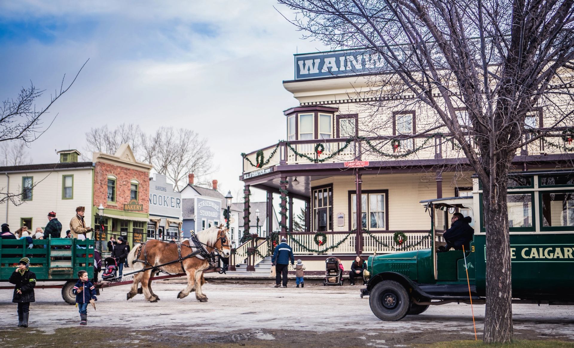 A horse-drawn wagon and people on the street at Christmastime at Heritage Park Historical Village in Calgary.