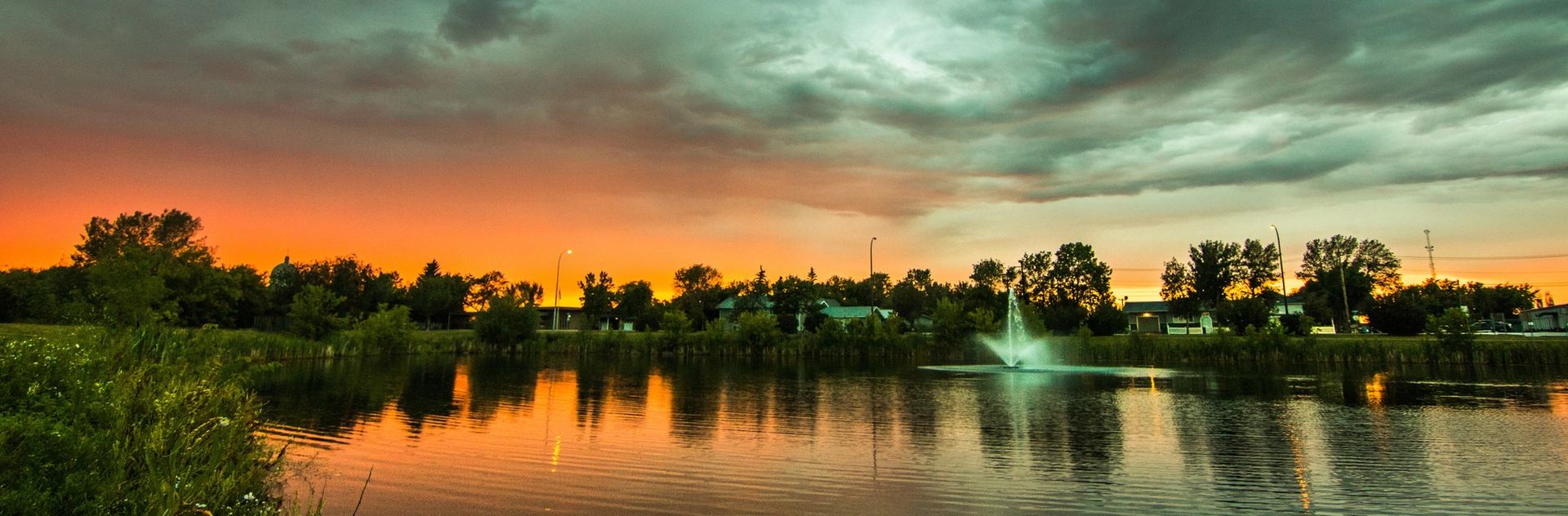 Town of Bonnyville reflecting on calm water at sunset.