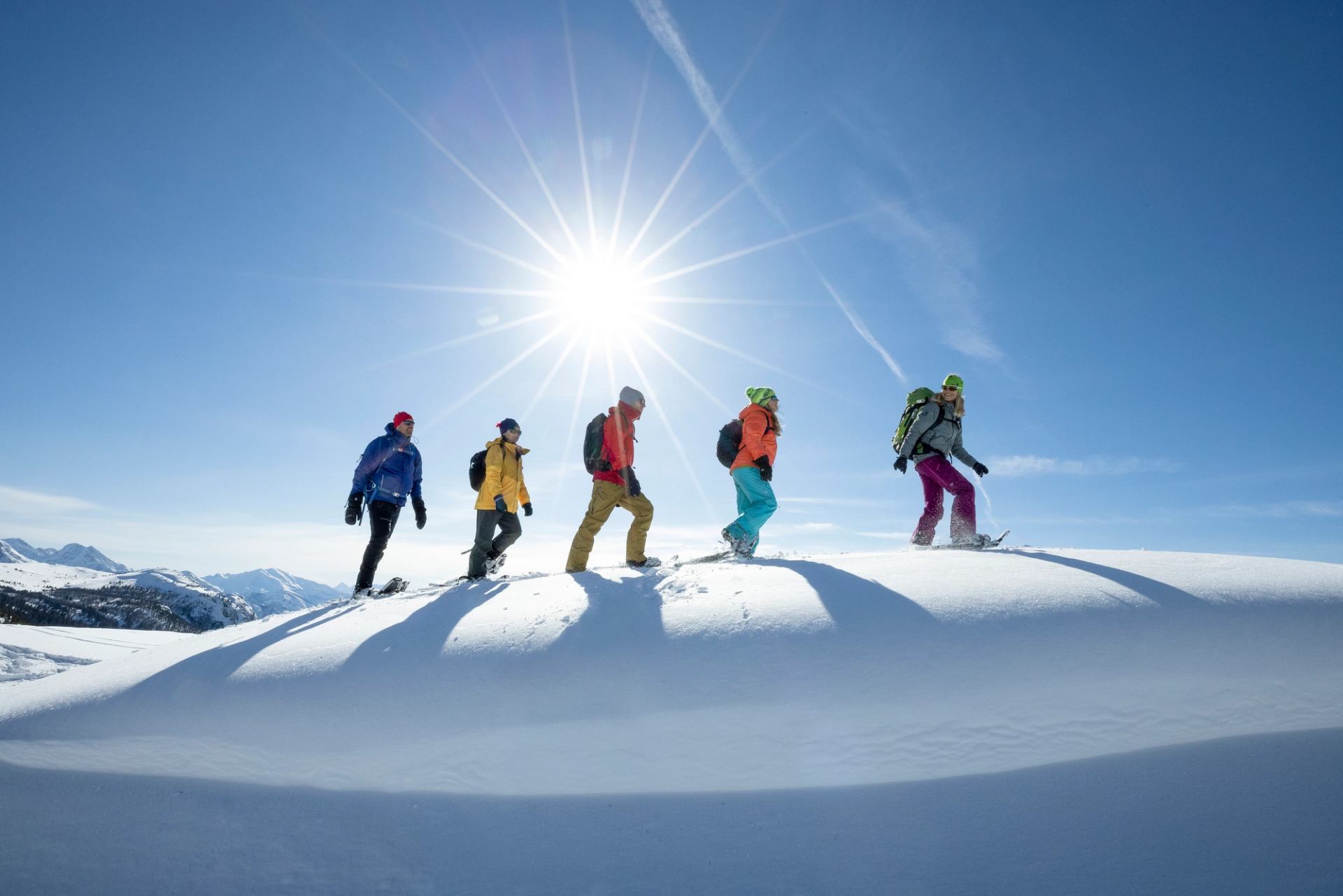 People follow their snowshoe guide along a snowy ridge in the Rockies.