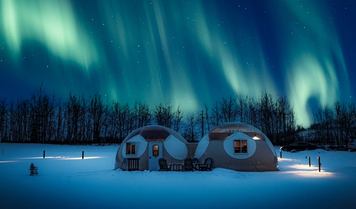 Two domes are lighted up with the auroras above in the night sky