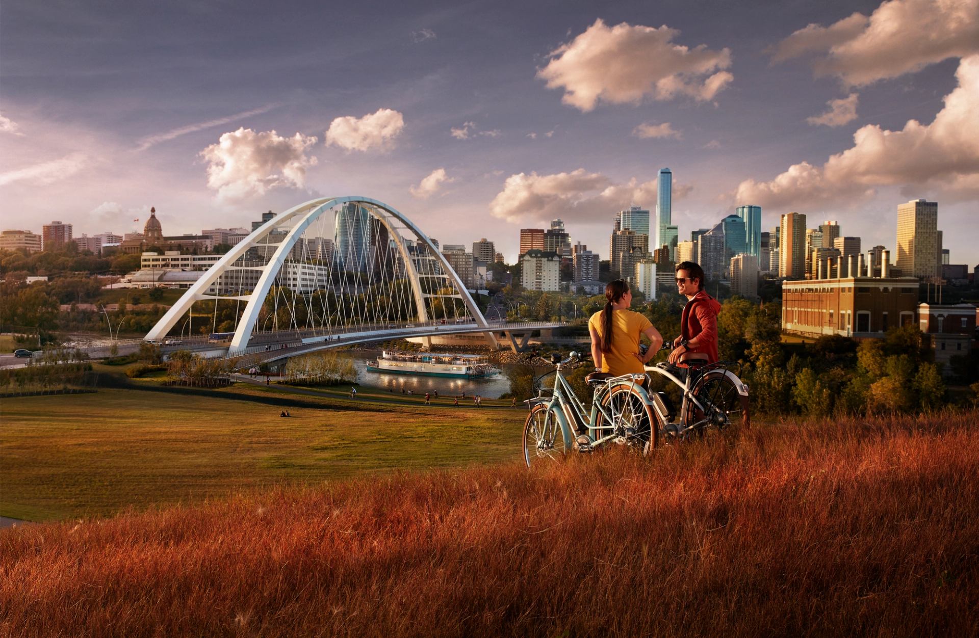 A couple enjoying the sunset with bicycles, and the Edmonton skyline in the background.