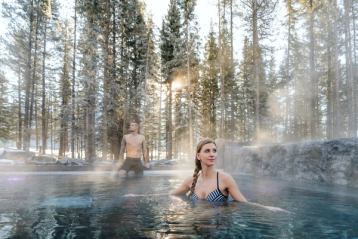 Two people enjoying the hot pools at Kananaskis Nordic Spa.