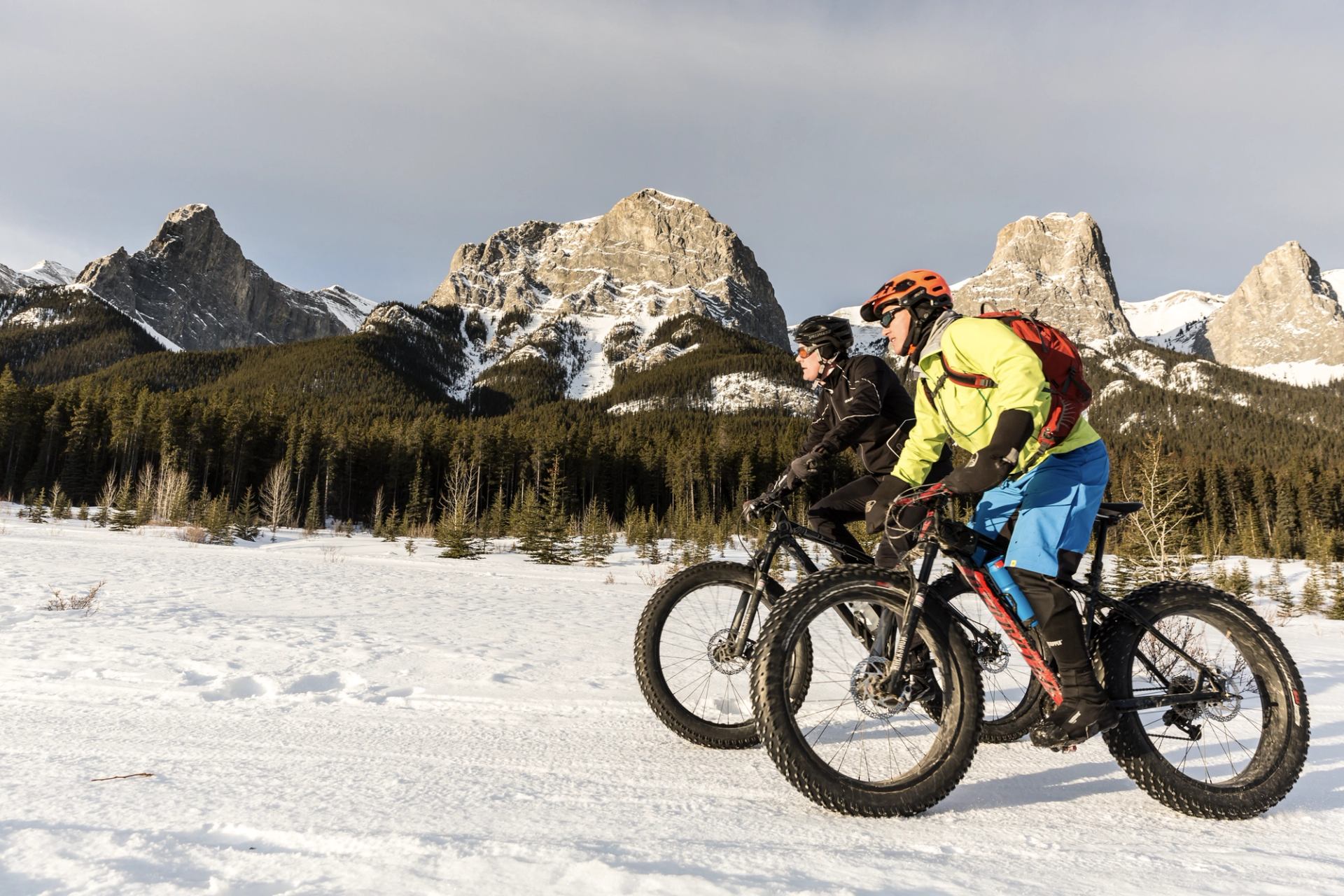 Two people fat biking with mountains in background near Canmore in Kananaskis Country.