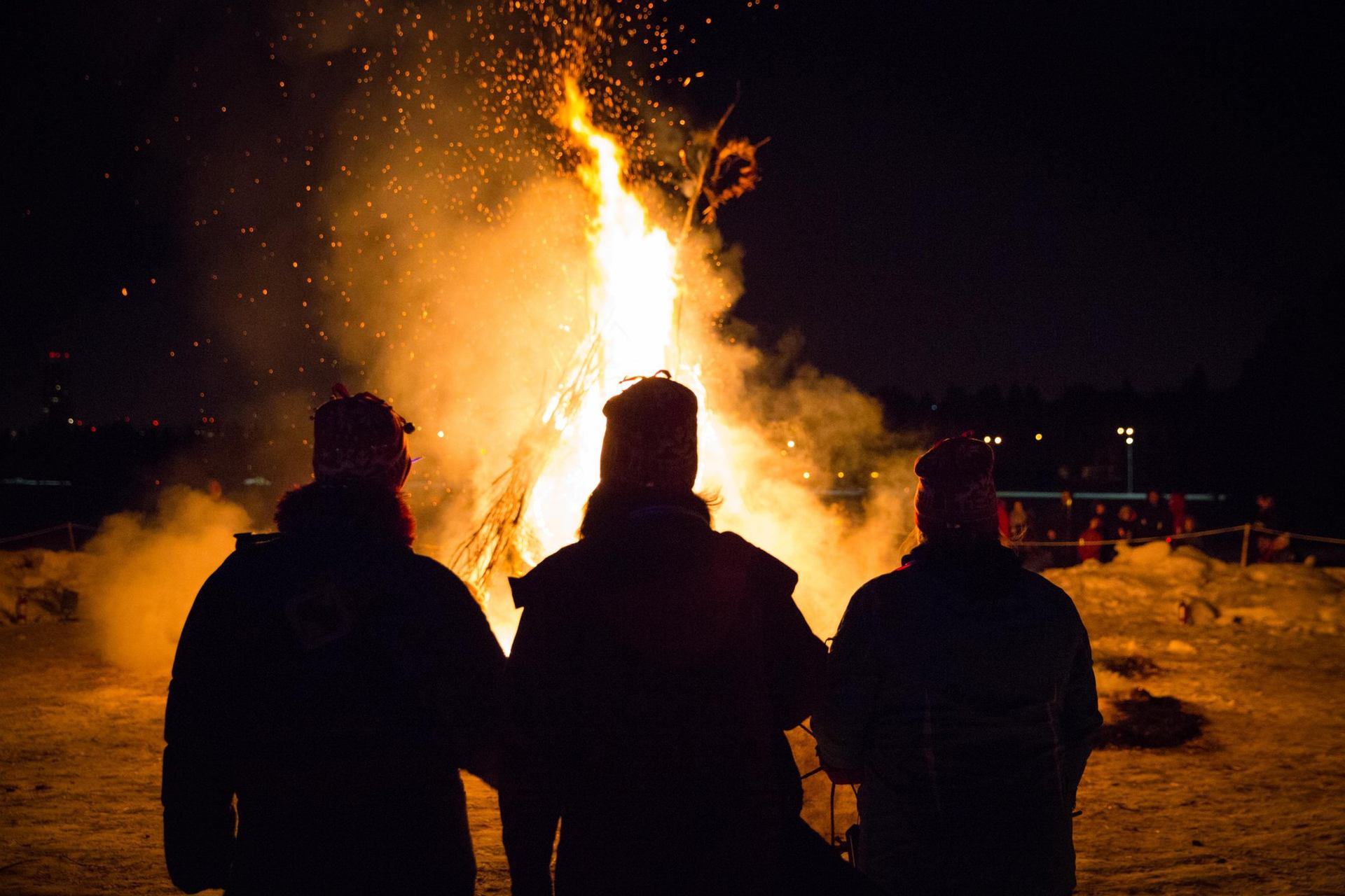 People watch a fire sculpture burn at night during the Silver Skate Festival.