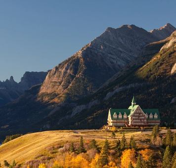 Historic hotel on a hill above a lake with a mountain view in the background.