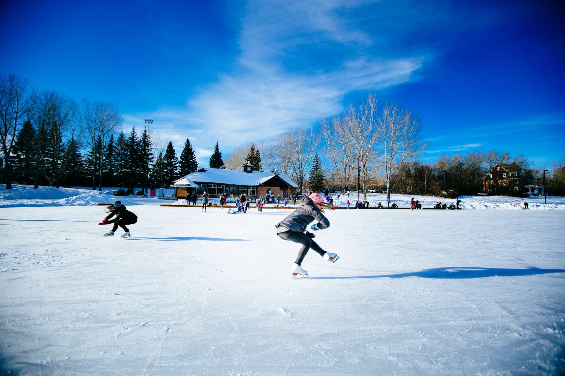 A woman skates on a frozen lake with other skaters in the background.