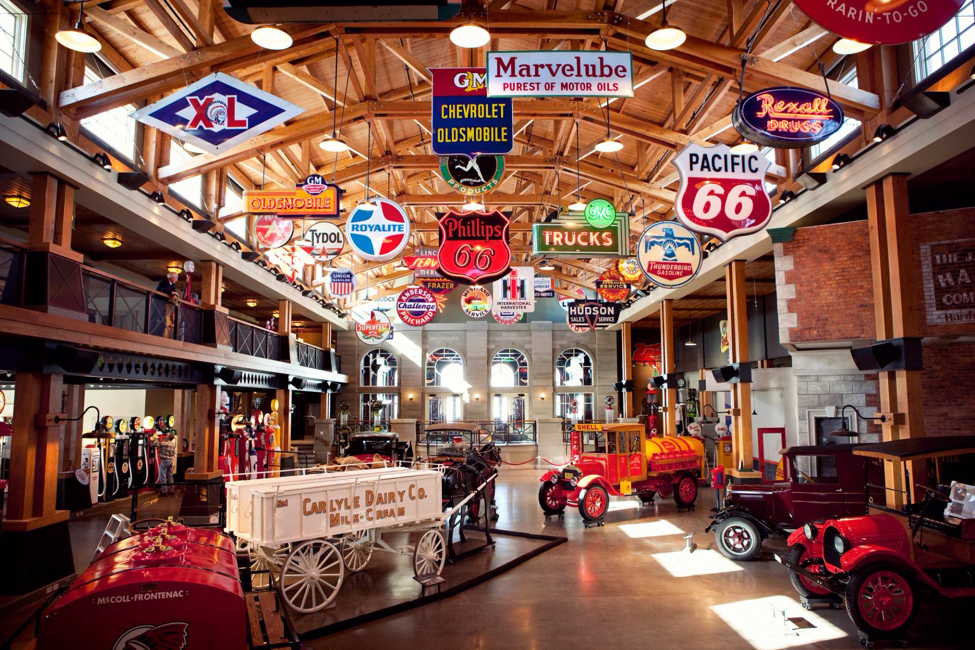 Interior view of a museum filled with old cars and gas station signage.