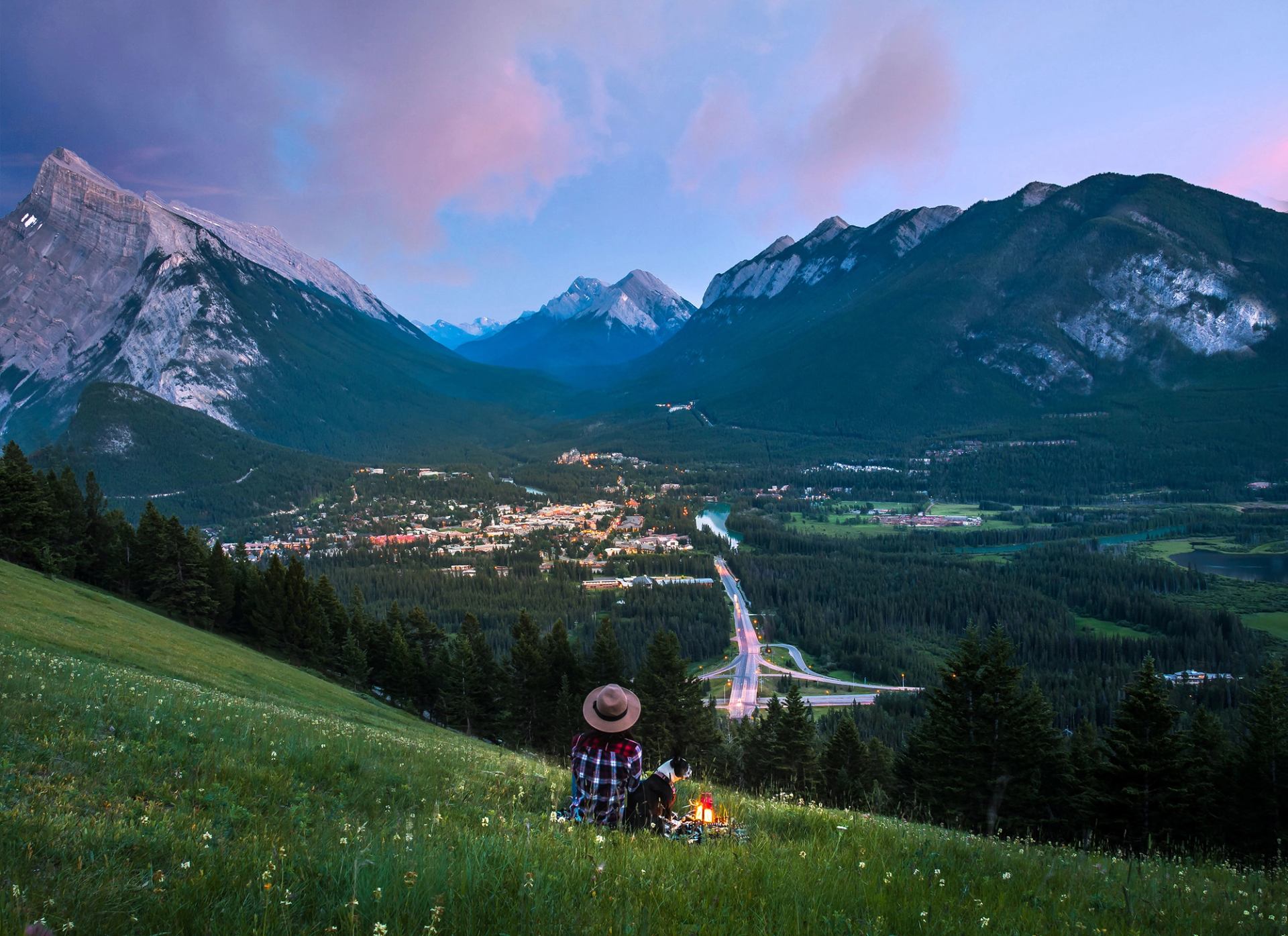 Woman and dog overlooking summer mountain town. Banff.