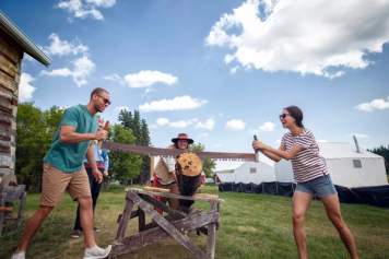 Couple sawing a log at Metis Crossing