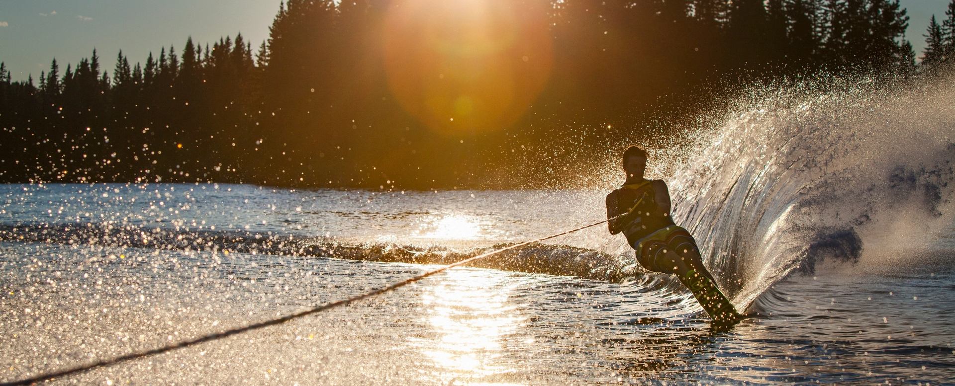 Man wakeboarding splashing up water at sunset on Island Lake.