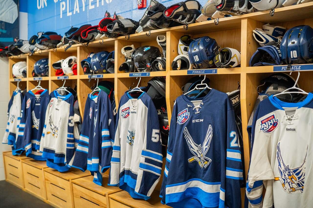 Canmore Eagles Junior "A" Hockey jerseys hanging plus other hockey equipment in a dressing room at the Canmore Recreation Centre.