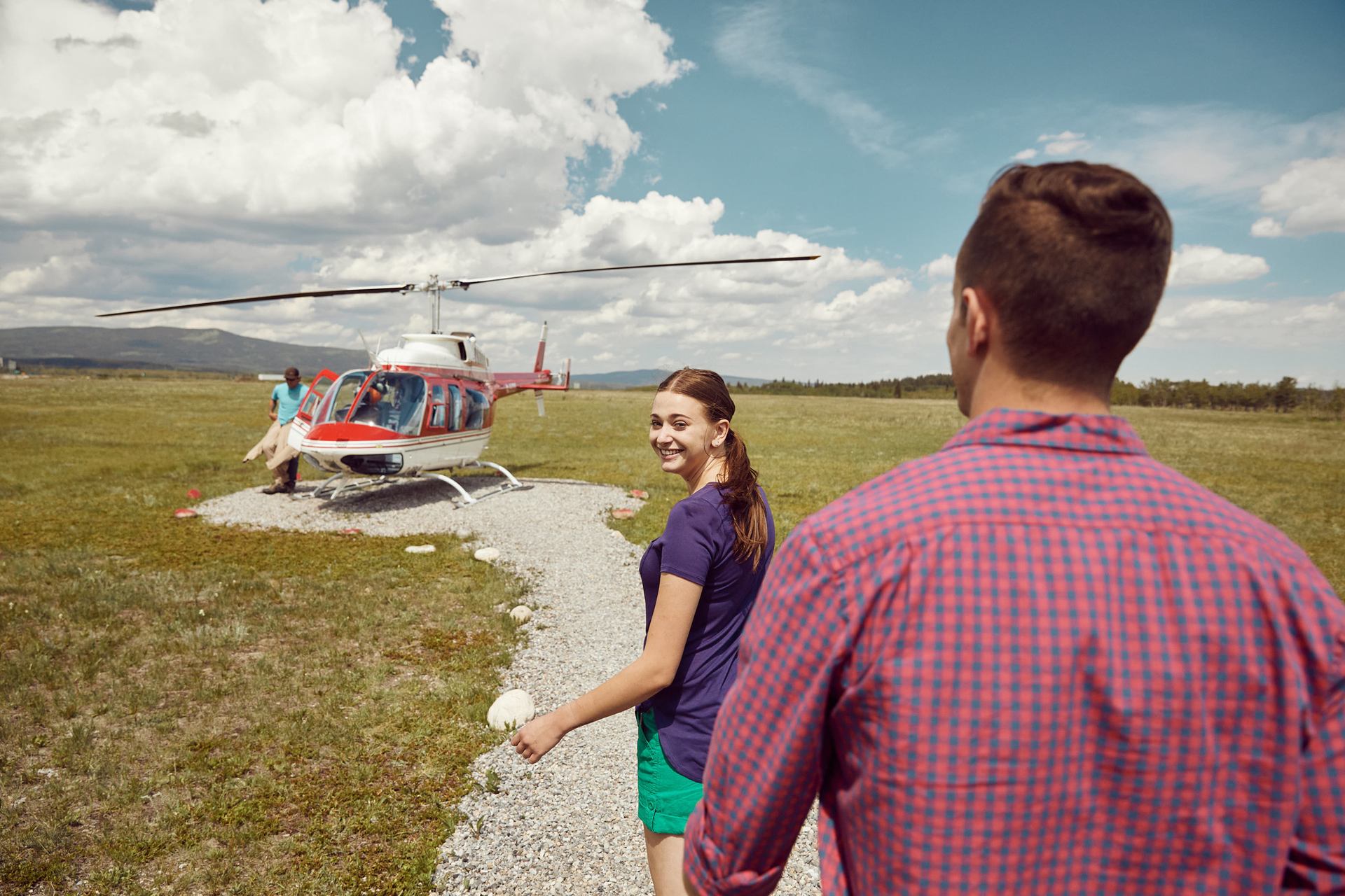 A couple approaches a helicopter ready to take off.