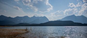 People swimming in Lower Kananaskis Lake surrounded by mountains in Kananaskis Country.