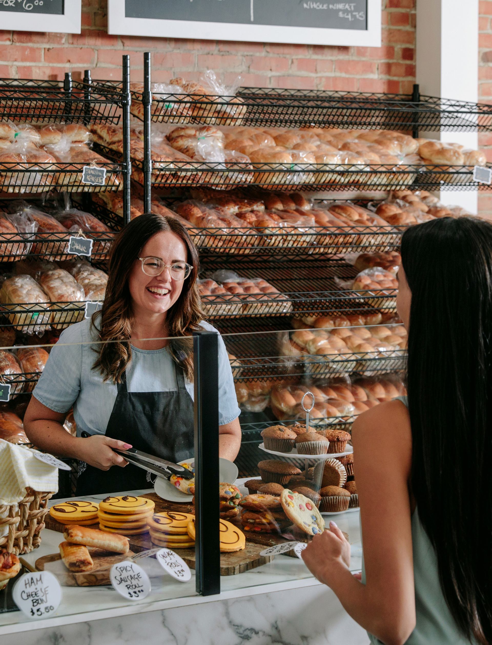 Customer ordering food at Redcliff Bakery and Eatery in Medicine Hat with fresh bread and pastries in the background.