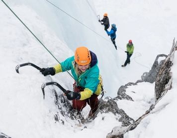 An ice climber ascending with other climbers at the base, while ice climbing at Tangle Falls in Jasper National Park