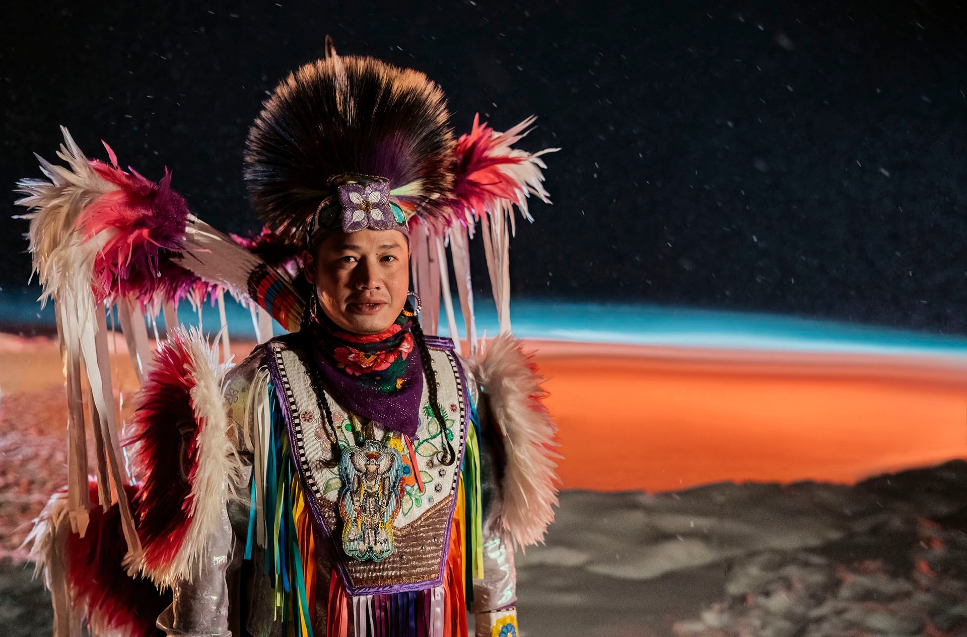 Indigenous dancer Patrick Mitsuing stands in his regalia in front of Sylvan Lake.