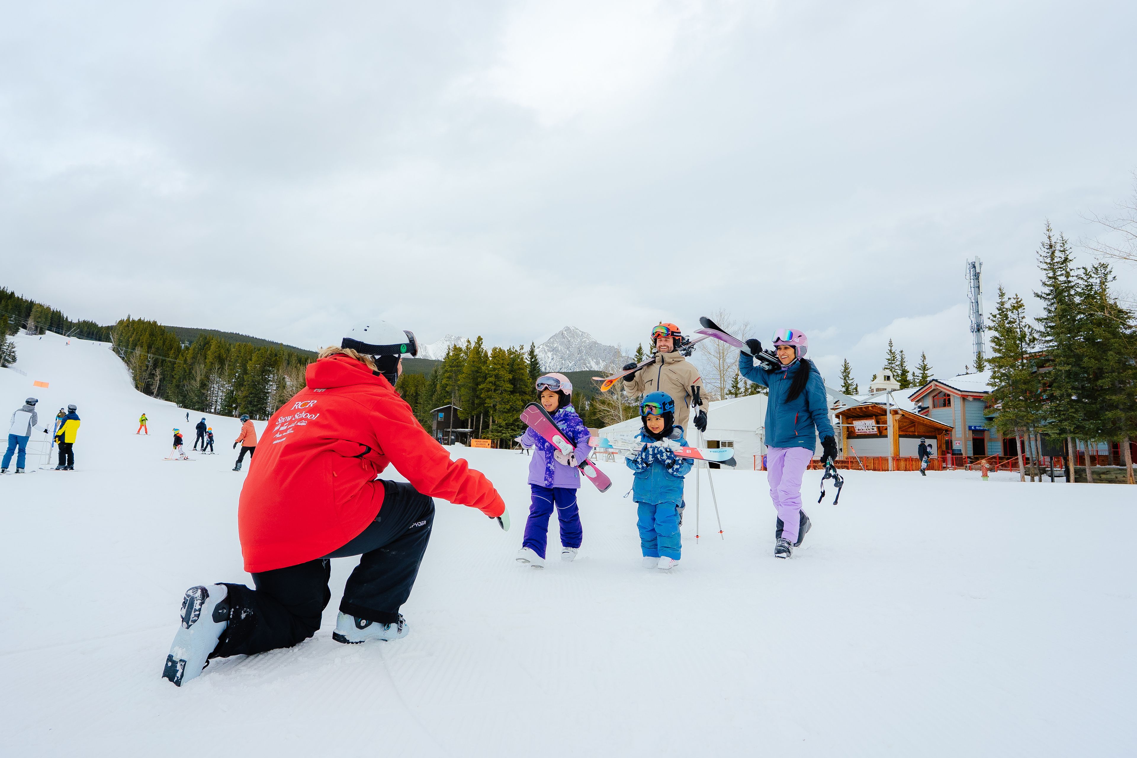 A ski instructor welcomes a family approaching the slopes at Nakiska Ski Area