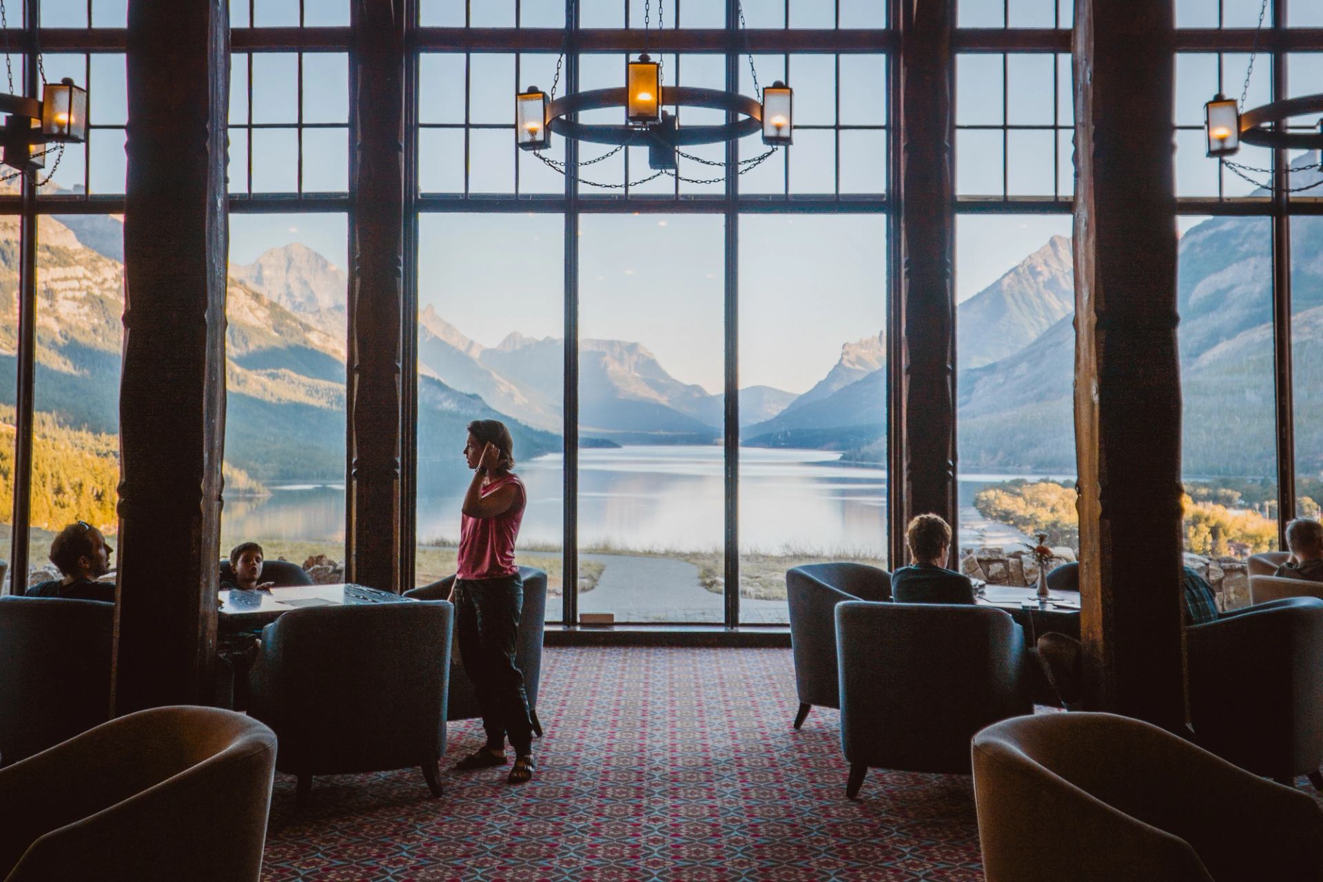 The interior of Prince of Wales Hotel in Waterton, with an exterior view of the lake and mountains.