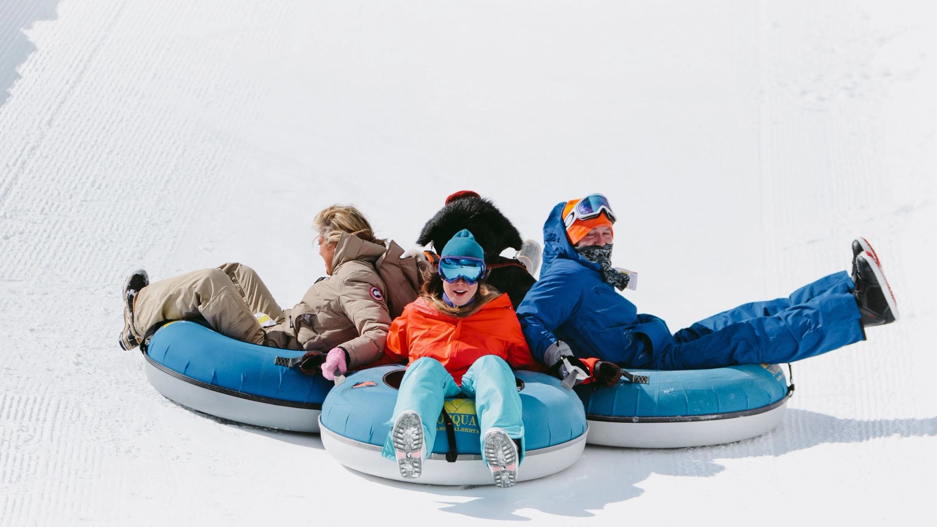 A family hangs on to each other's tubes while coming down a run at the Tube Park at Mount Norquay in Banff National Park