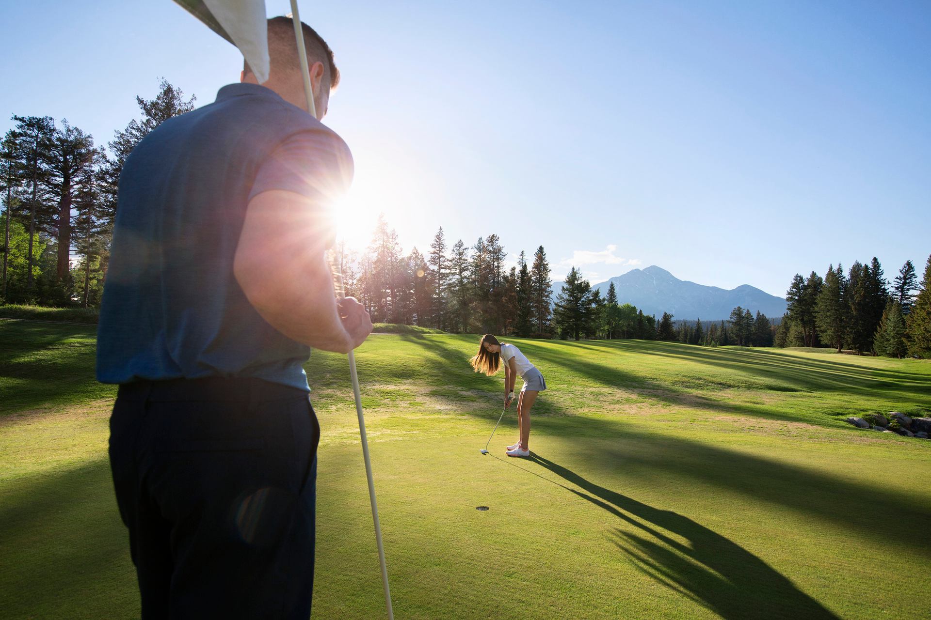 A man holds the flag on a golf course.