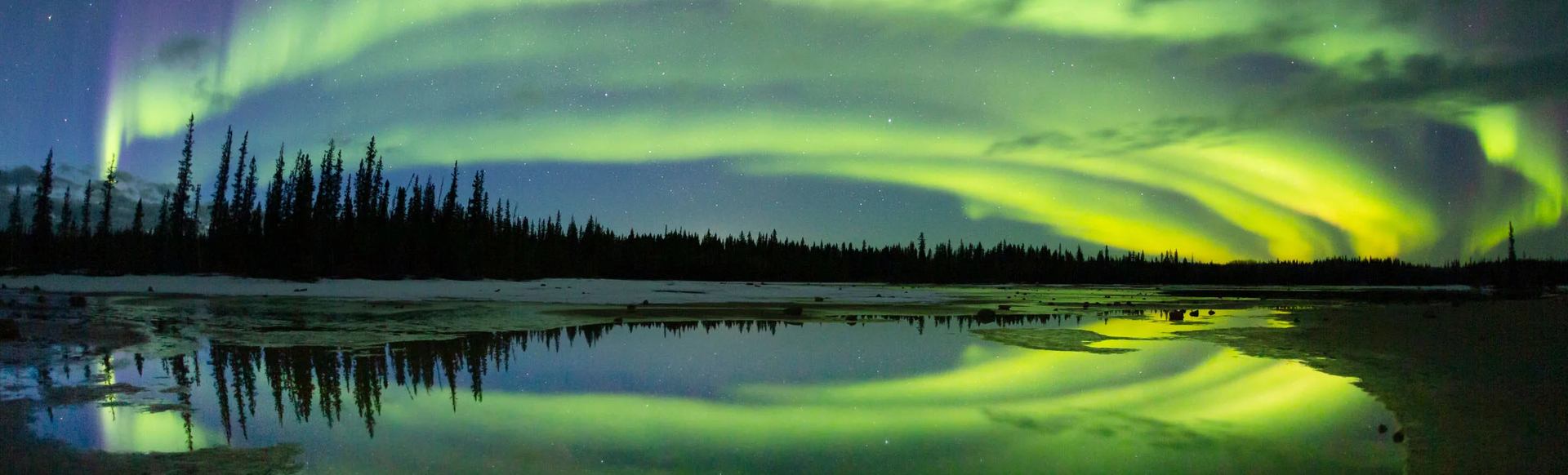 Northern lights stretch across the sky over a lake in Wood Buffalo National Park.