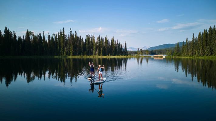 Two people standup paddle boarding (SUP) in Kelley's Bathtub, Northern Rockies, William A. Switzer Provincial Park.