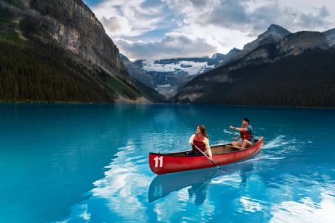 A couple paddles across the turquoise waters of Lake Louise.