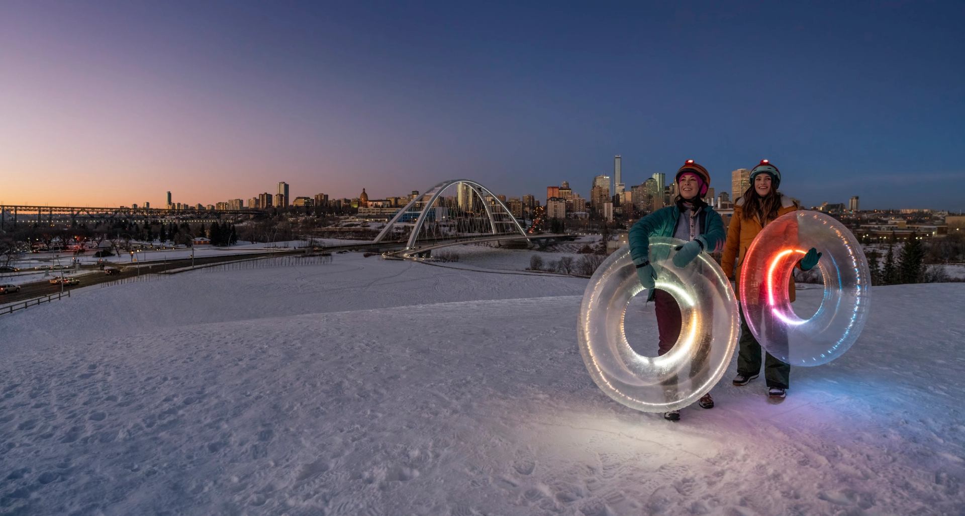 People tubing in front of Edmonton skyline.