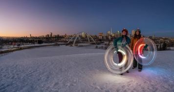 People tubing in front of Edmonton skyline.