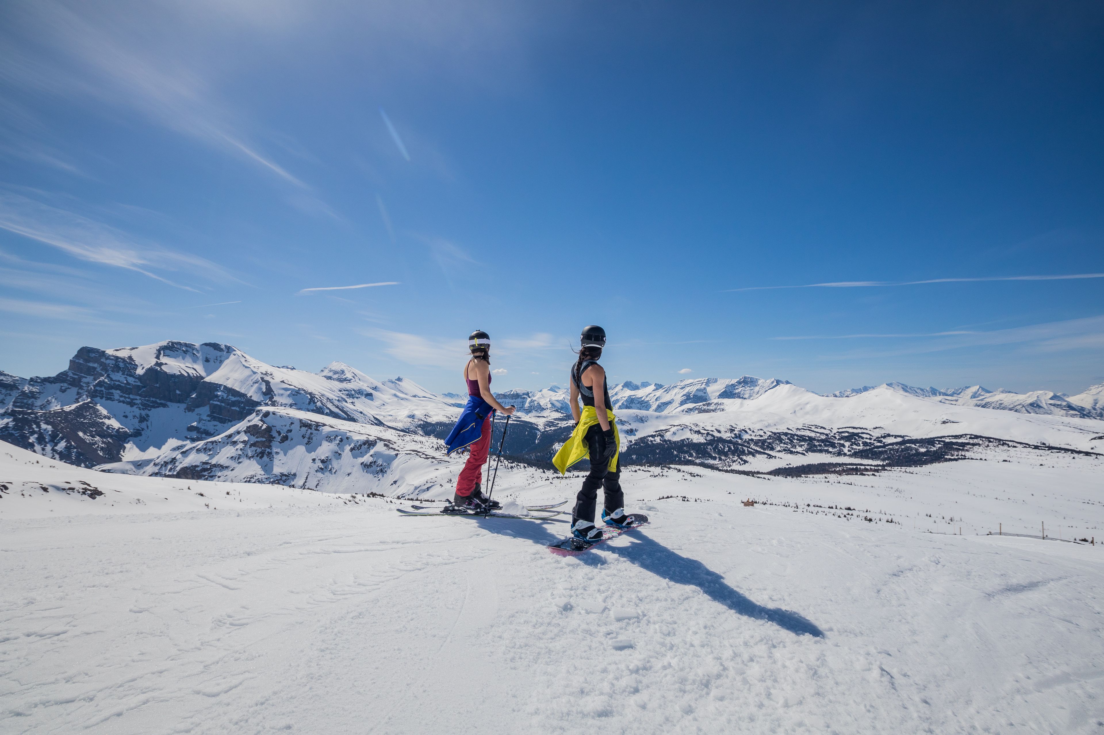 A skier and snowboarder, jackets around their waists, prepare to ski at Banff Sunshine Village.