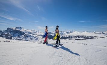 A skier and snowboarder, jackets around their waists, prepare to ski at Banff Sunshine Village.