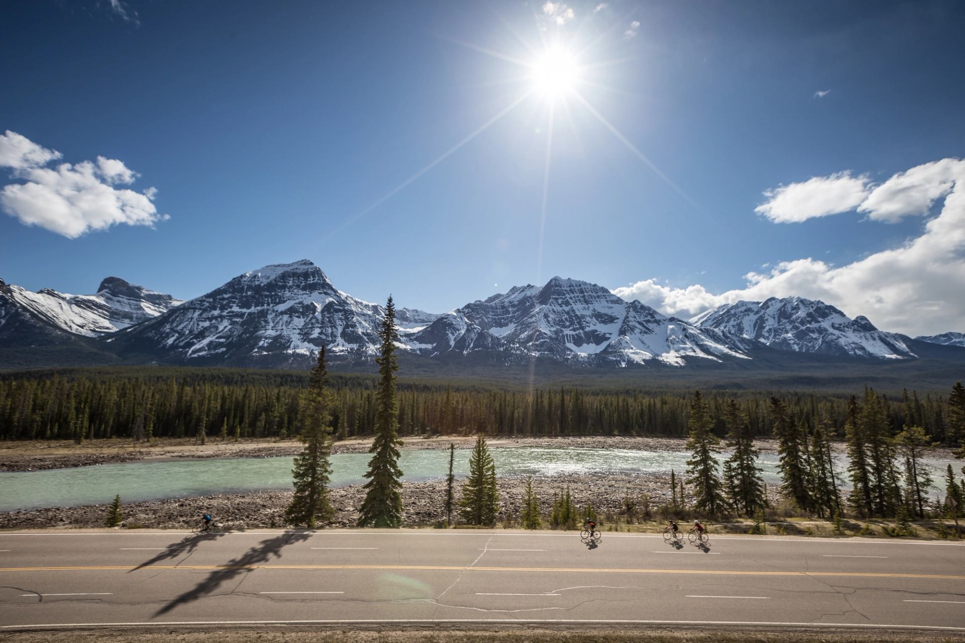 Group of cyclists riding on the Icefields Parkway with views of the mountains in Jasper National Park.