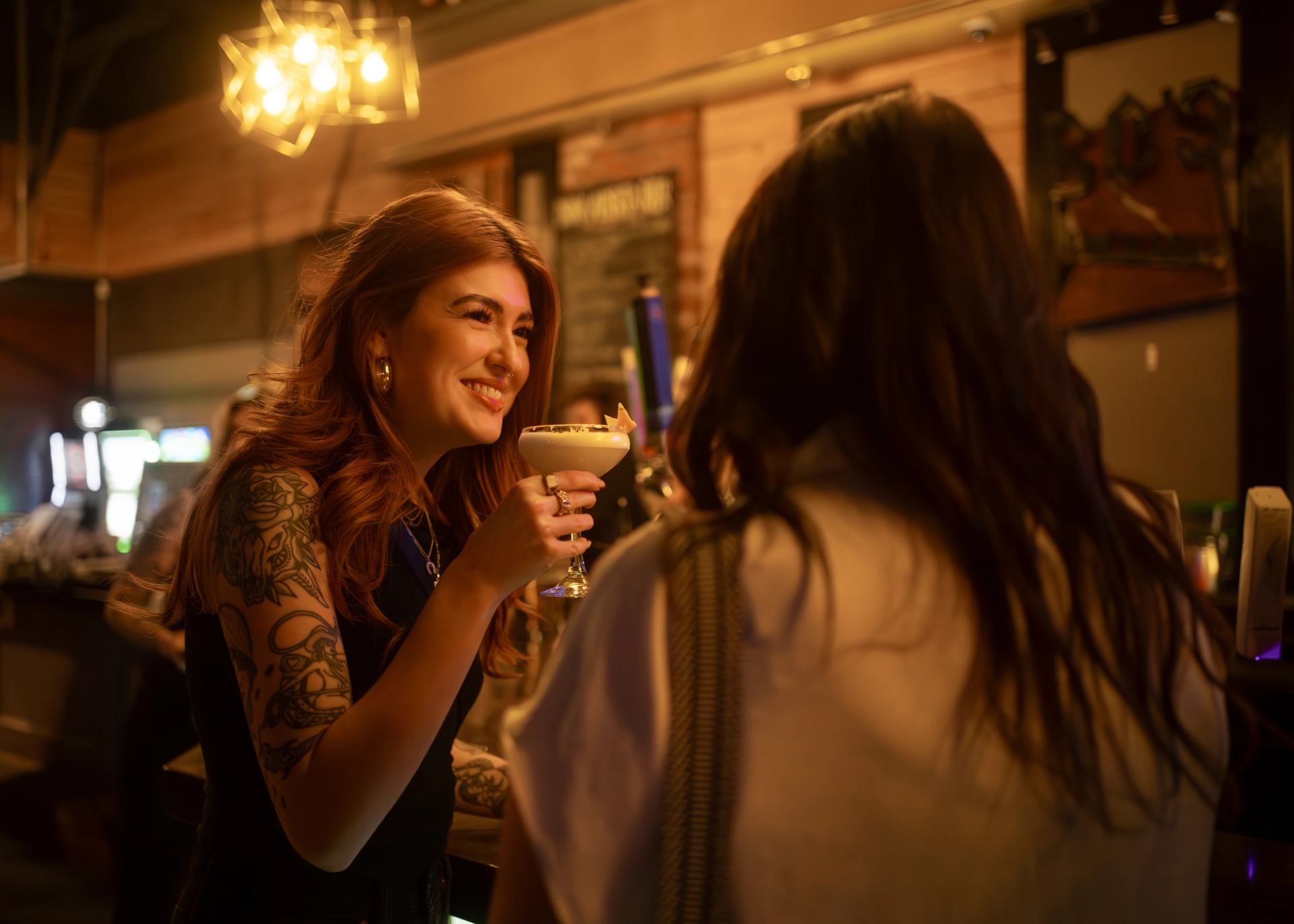 Two people chat and sip cocktails in warm lighting at Bo's Bar and Stage in Red Deer.