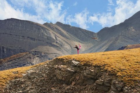 Female doing yoga in front of mountains