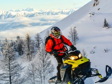 Snowmobiler climbing the side of a mountain in Banff.