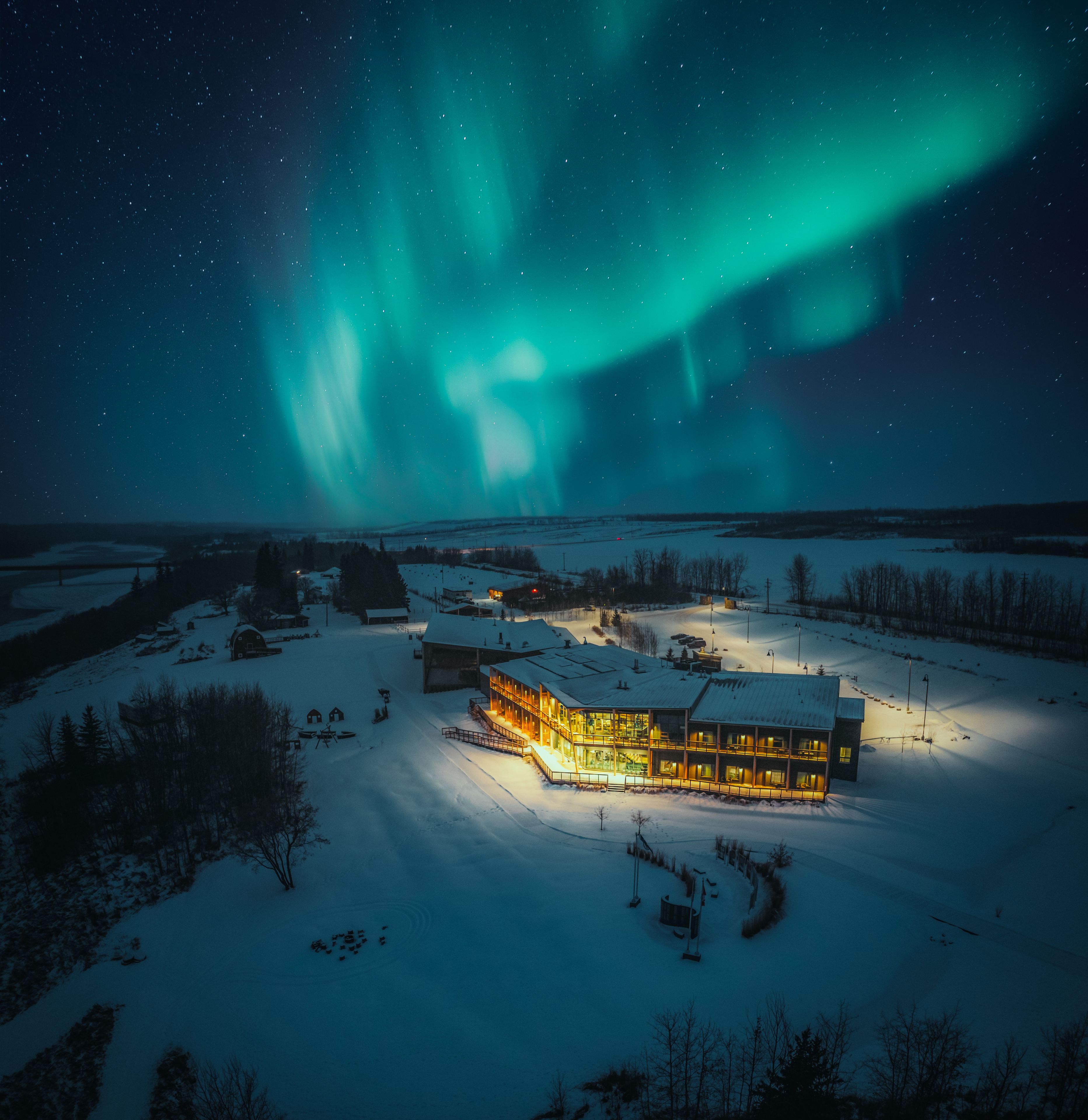 The northern lights shine over the lodge at Metis Crossing on a winter night.