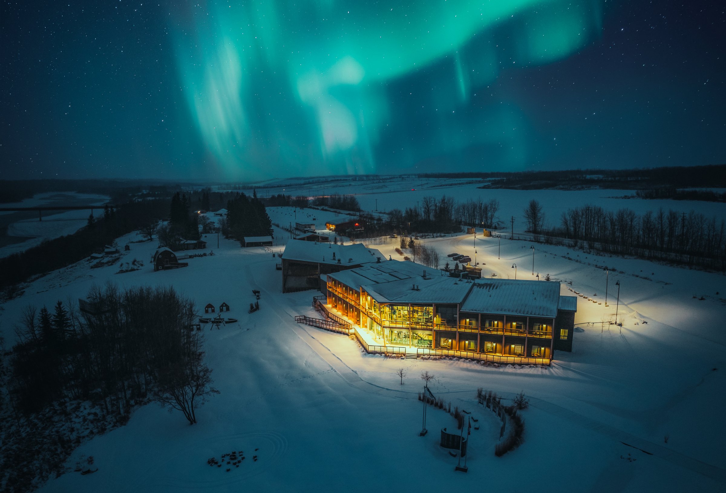 The northern lights shine over the lodge at Metis Crossing on a winter night.