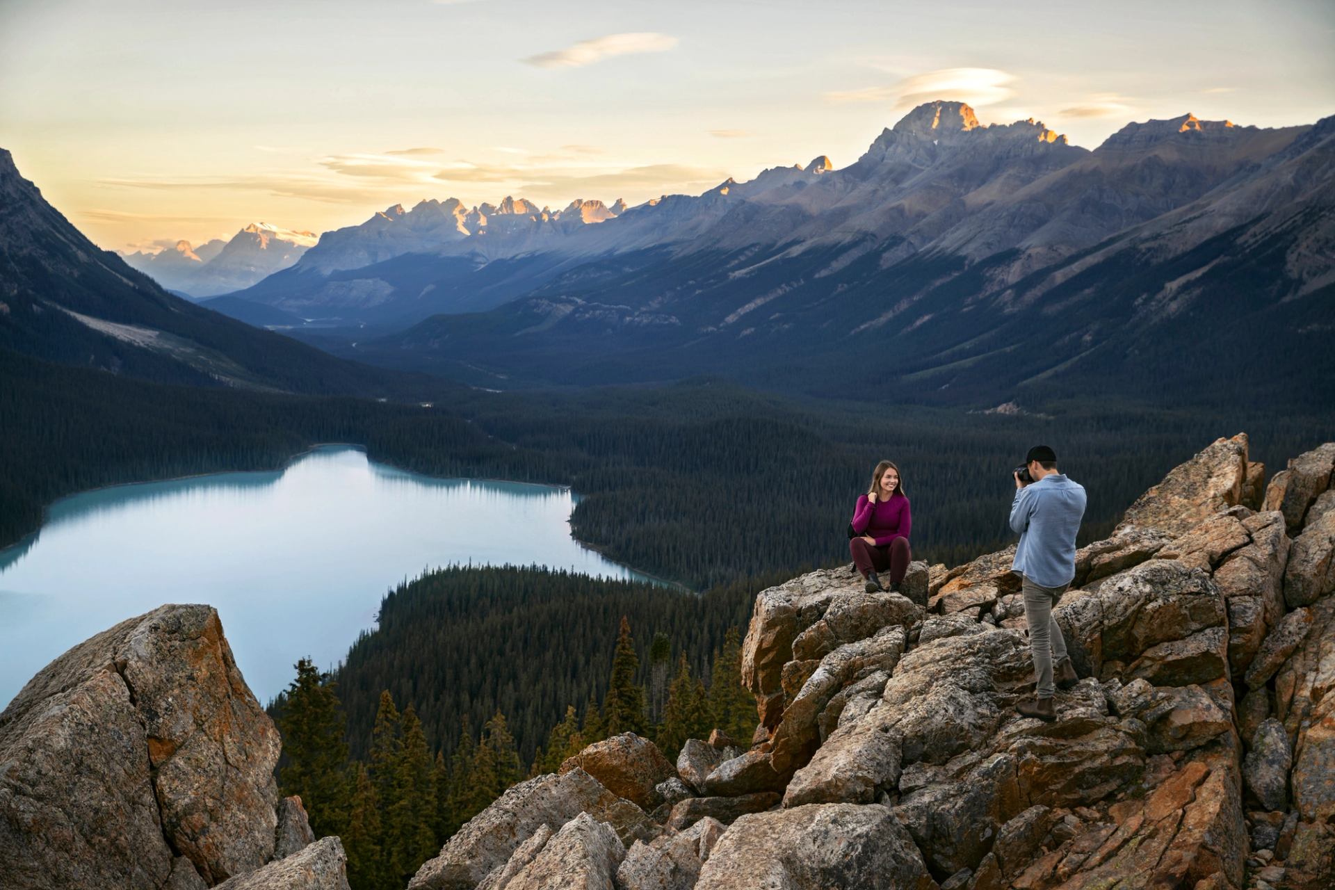 A couple take pictures while sitting on the rocks overlooking Peyto Lake in Banff National Park.