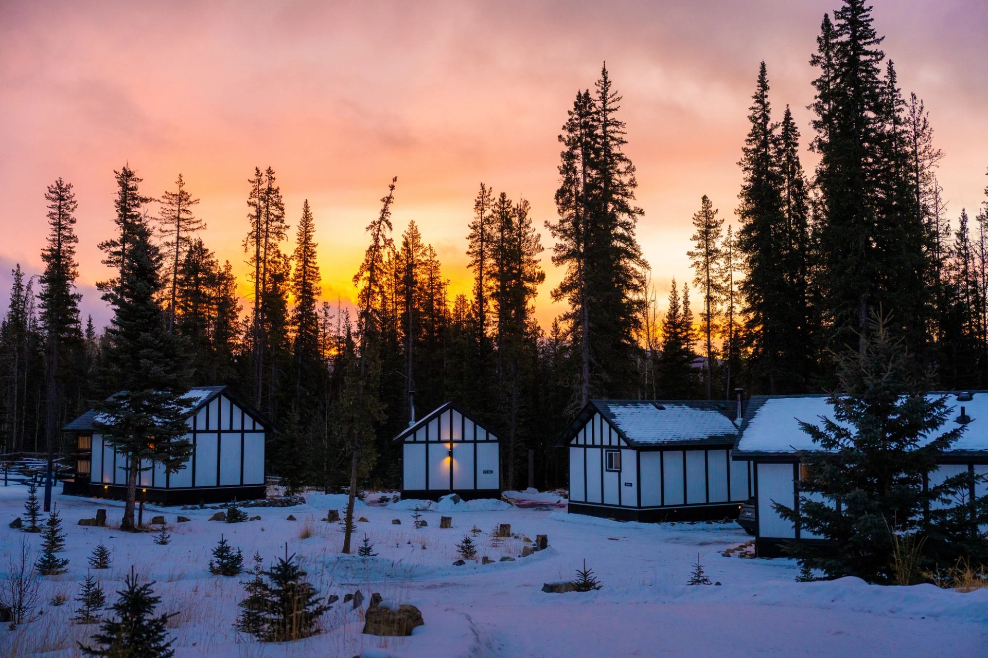 An orange-pink sunset glows behind the cabins at Expanse Cottages.
