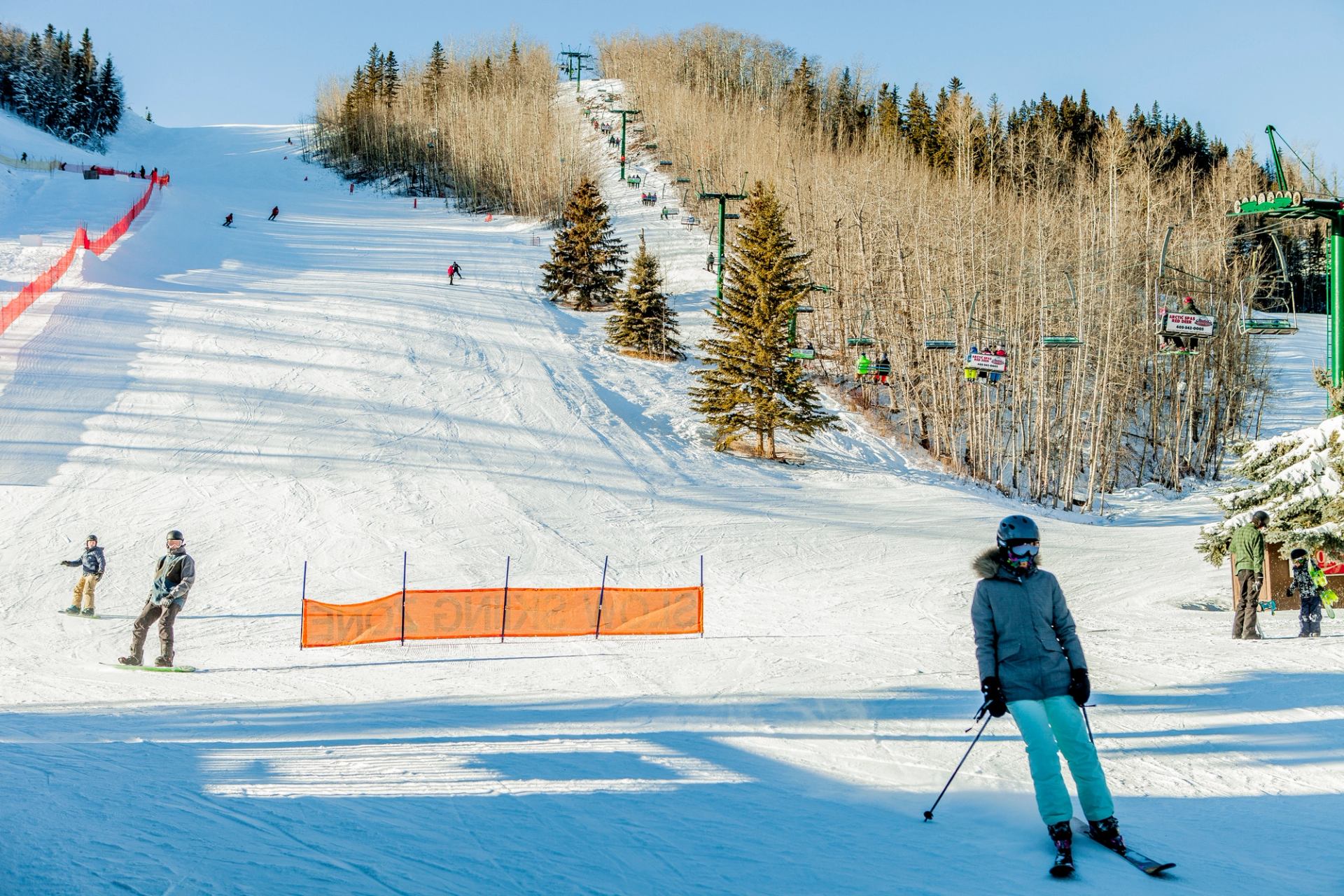 Skiers and snowboarders at the end of the run at a ski resort.