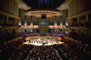 Wide angle view of lit theatre during musical performance.