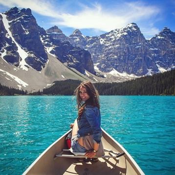 Woman sitting in a canoe on Moraine Lake surrounded by mountains in Banff National Park