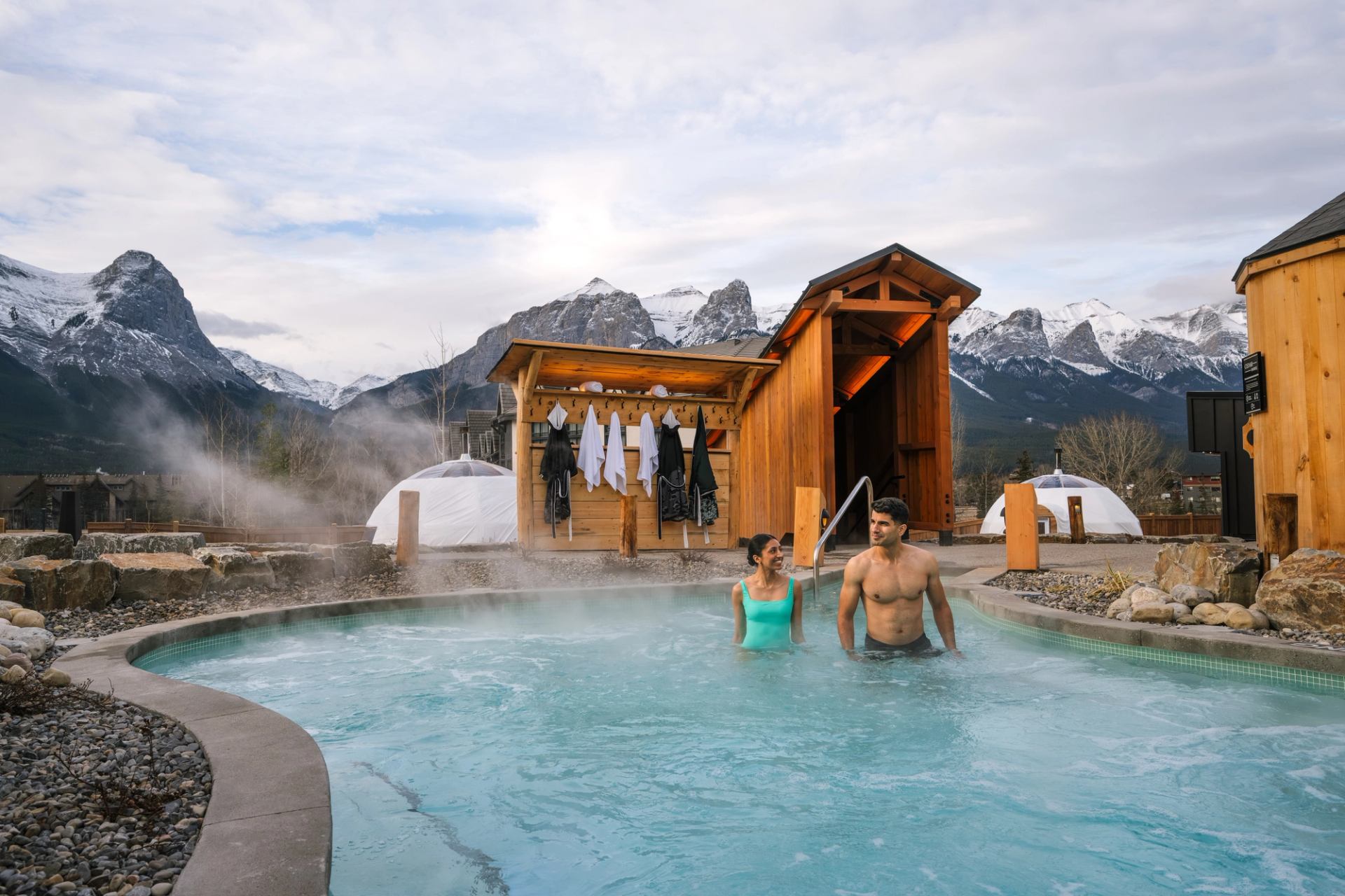 A couple bathe in a nordic pool at Everwild Canmore - Nordic Spa & Hotel.