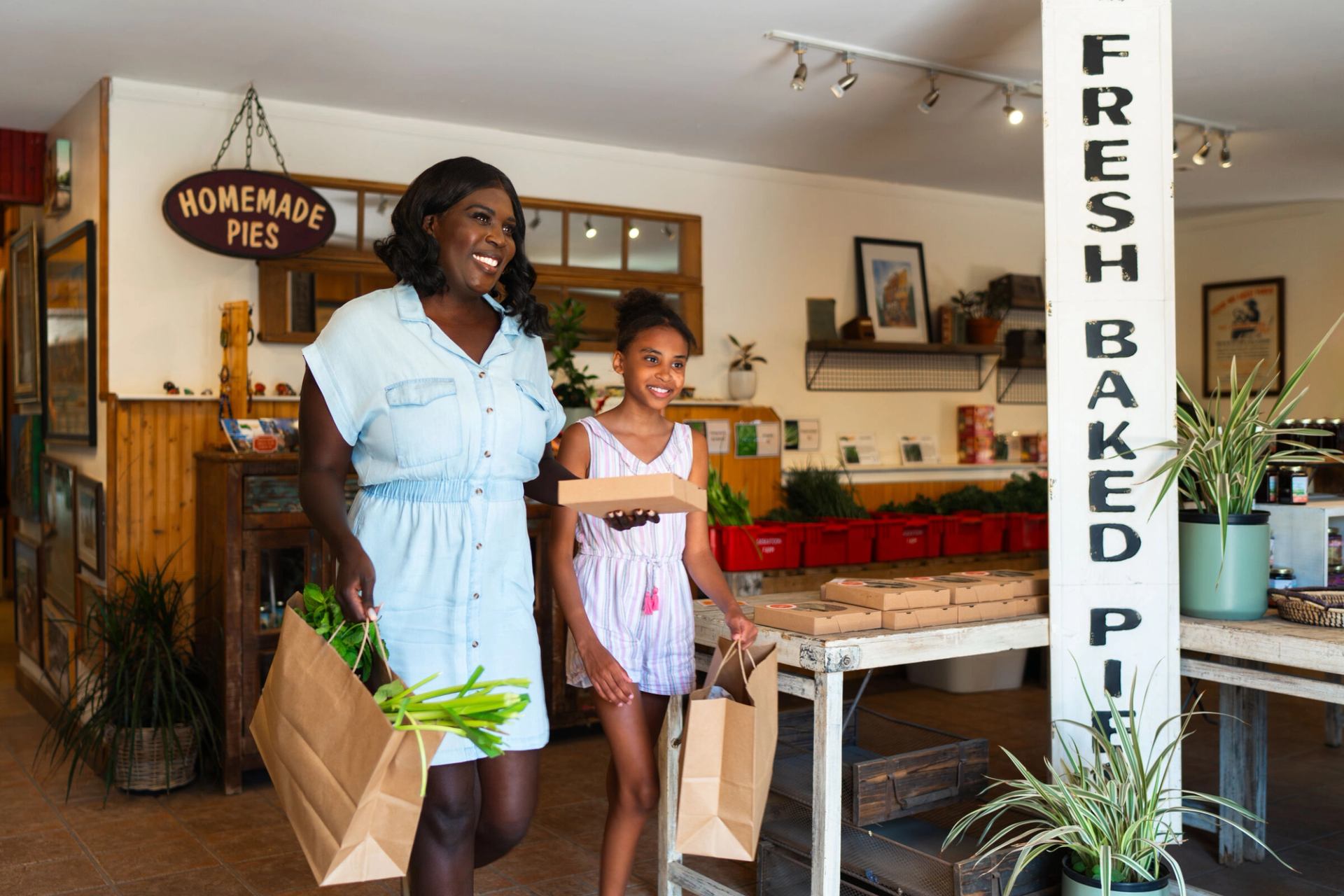 A mother and daughter walk out of the shop at Saskatoon Farm with pie and fresh ingredients.