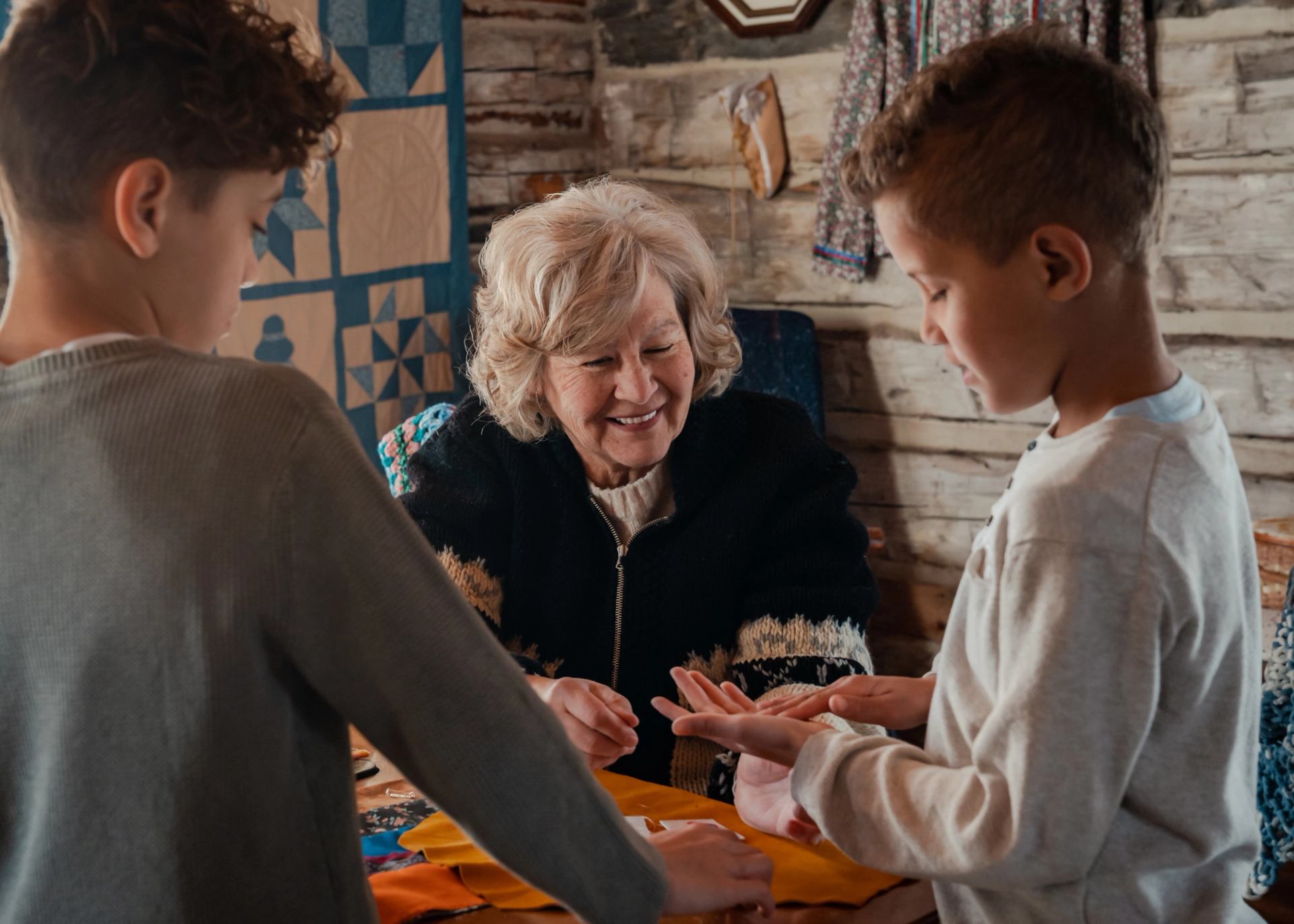 Indigenous woman showing children how to sew and make crafts at Métis Crossing.