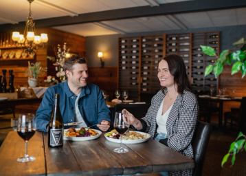 Man and woman enjoying a meal and glass of wine at a restaurant