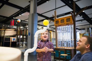 A father and son smiling while they play with a Science Centre interactive display.