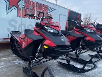 A row of snowmobiles in front of a trailer.