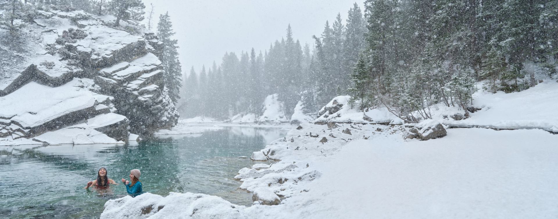 Two women taking a winter cold plunge in Canoe Meadows, Kananaskis.