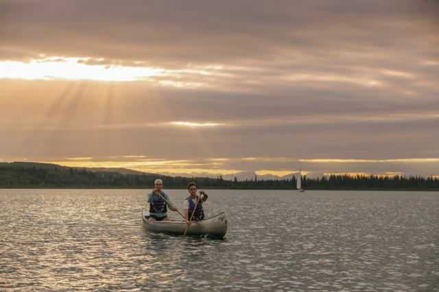 Two people paddle a canoe on the Glenmore Reservoir at sunrise in Calgary.